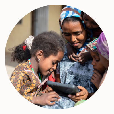 Women and a young girl gather around a tablet.