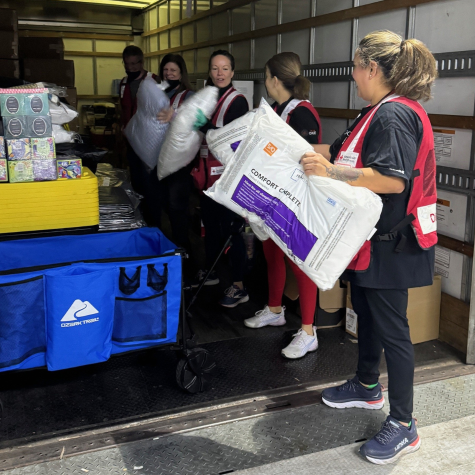 People in Red Cross vests pack a truck with supplies. 