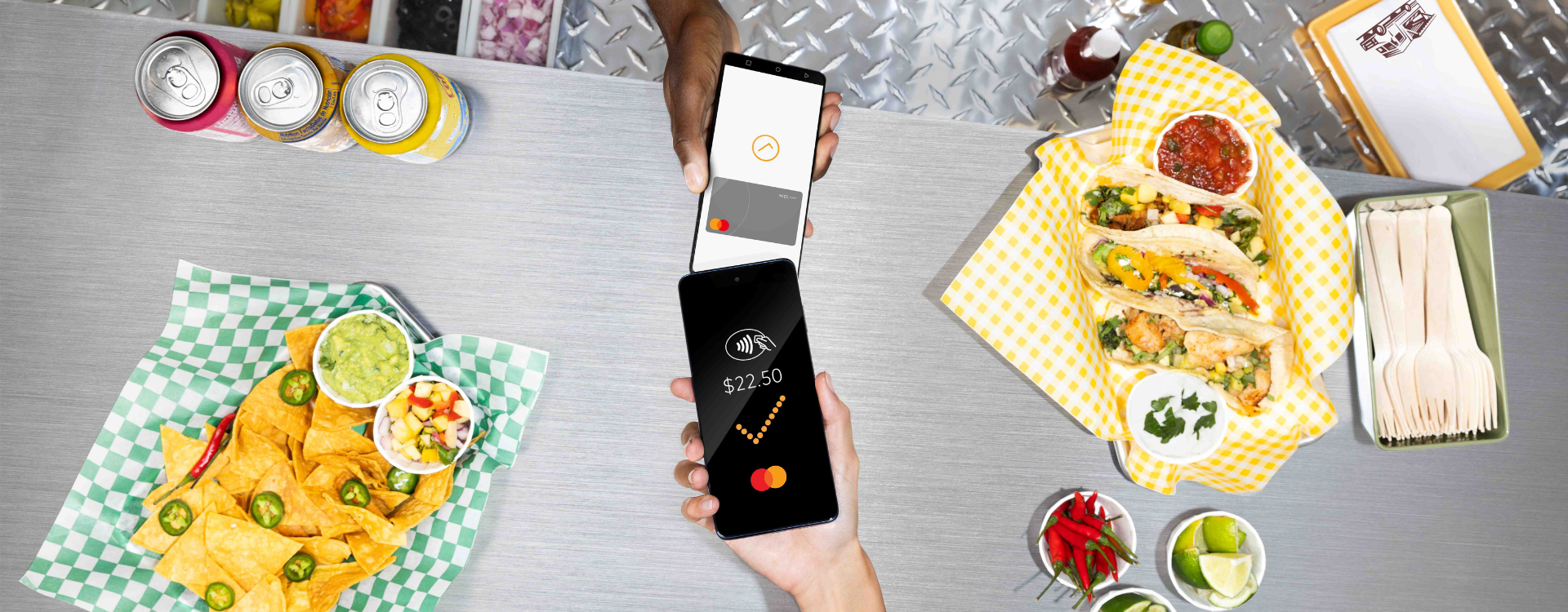 A person holding a smartphone taps it against another smartphone over a food truck counter.