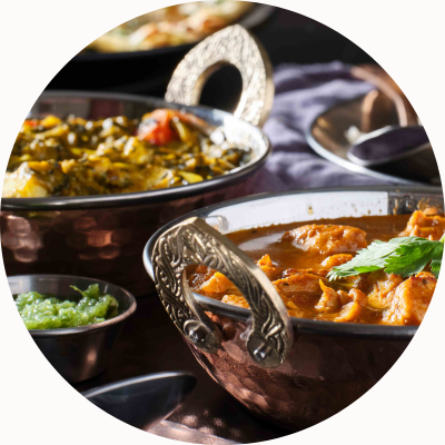 Dishes of India food in silver embossed bowls.