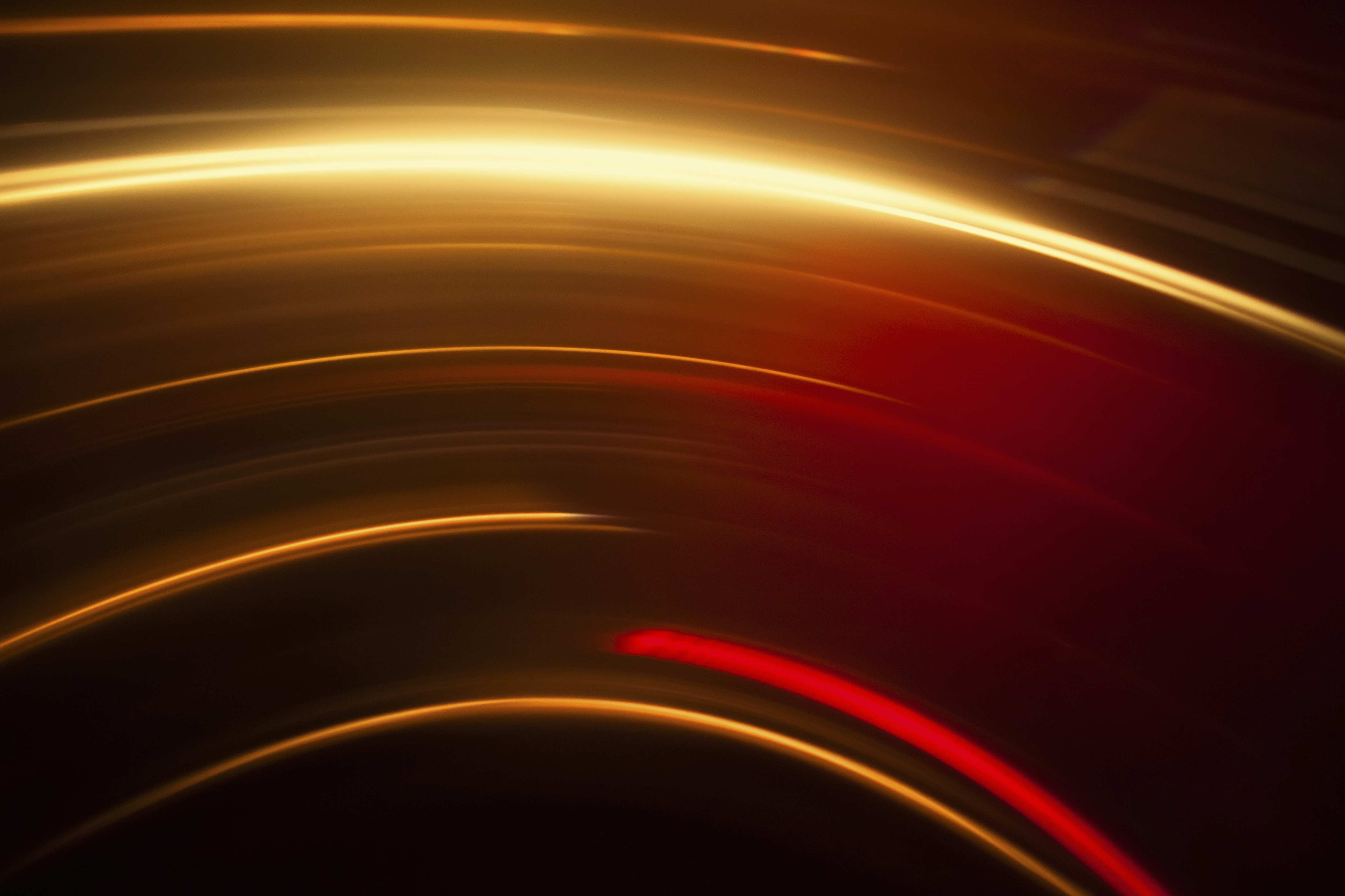 Abstract image of vibrant red and gold light trails against black background