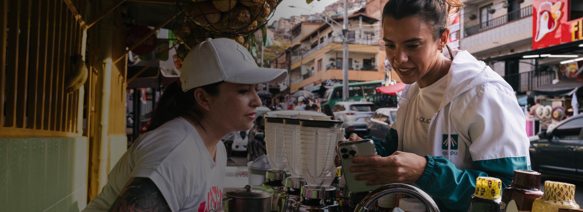 A street vendor selling blended juice drinks looks at a smartphone held by Mercedes Bidart, CEO and co-founder of Quipu.