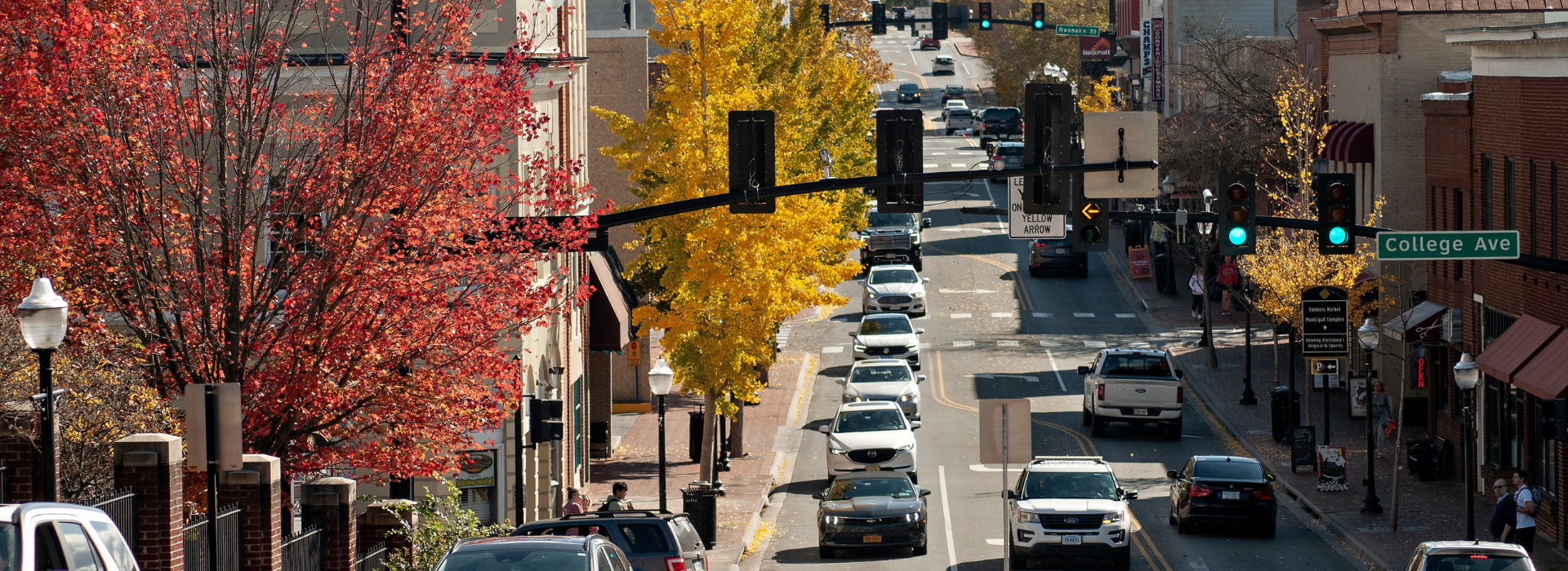 Cars on Blacksburg's main street during the fall as the trees lining the road are turning colors. 