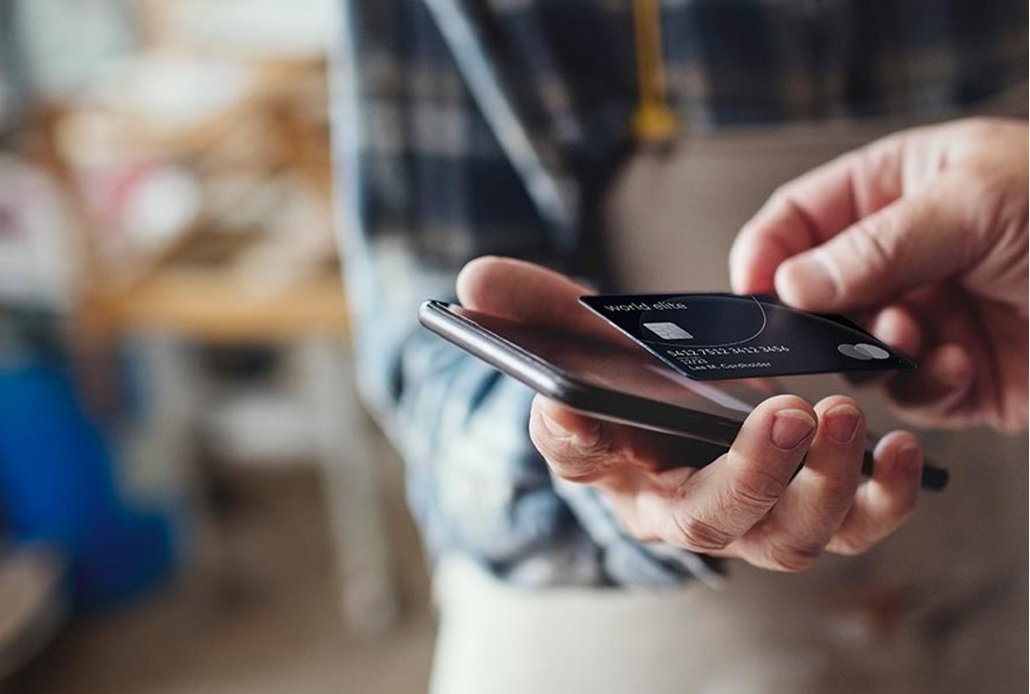 A person taps their credit card on a smartphone.