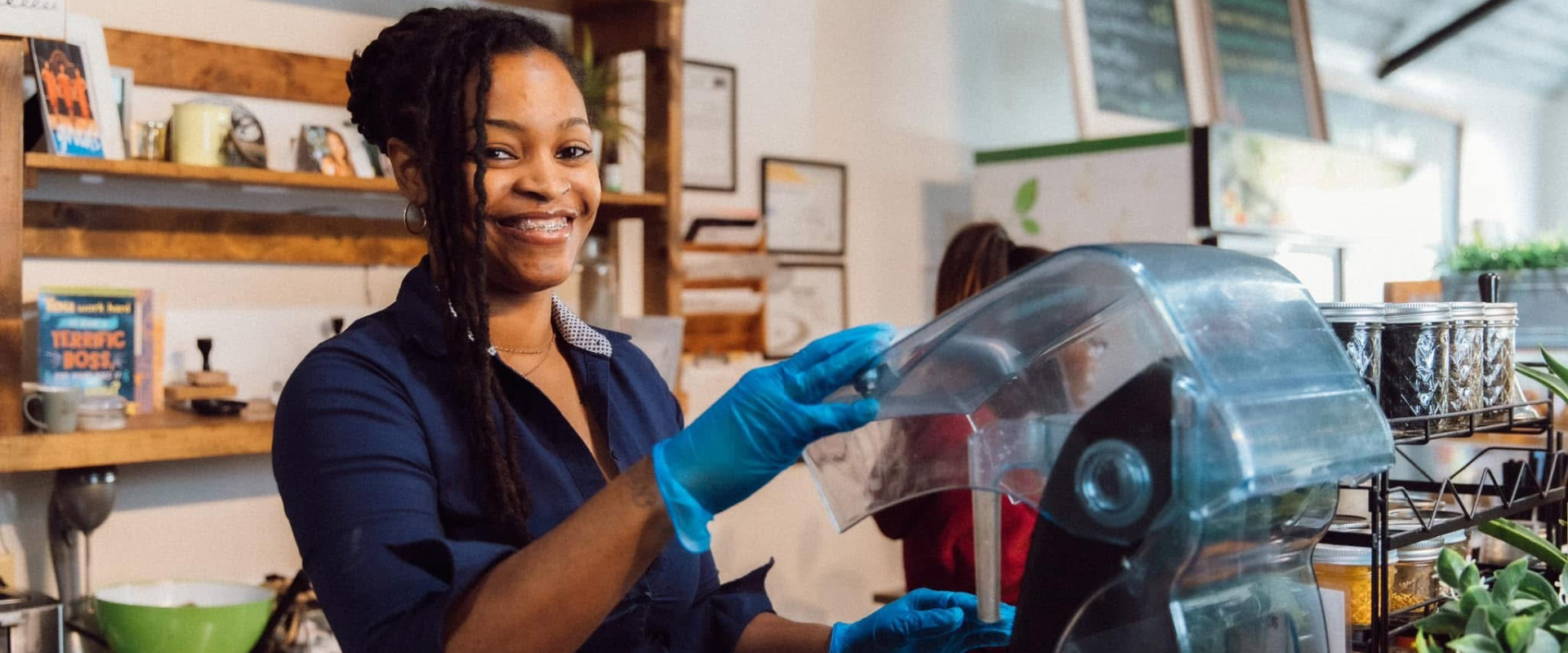 Kenesha Lewis stands at a blender in her store and smiles.