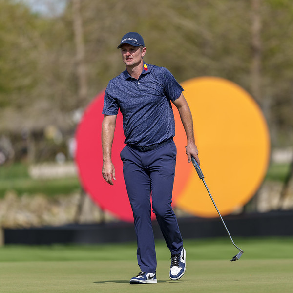 Justin Rose walks the green in front of a large Mastercard logo.
