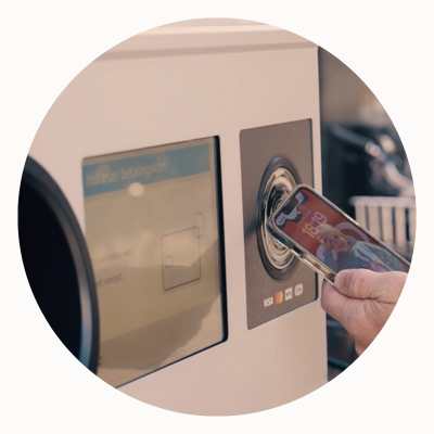 A person taps their phone at a TOMRA reverse vending machine.