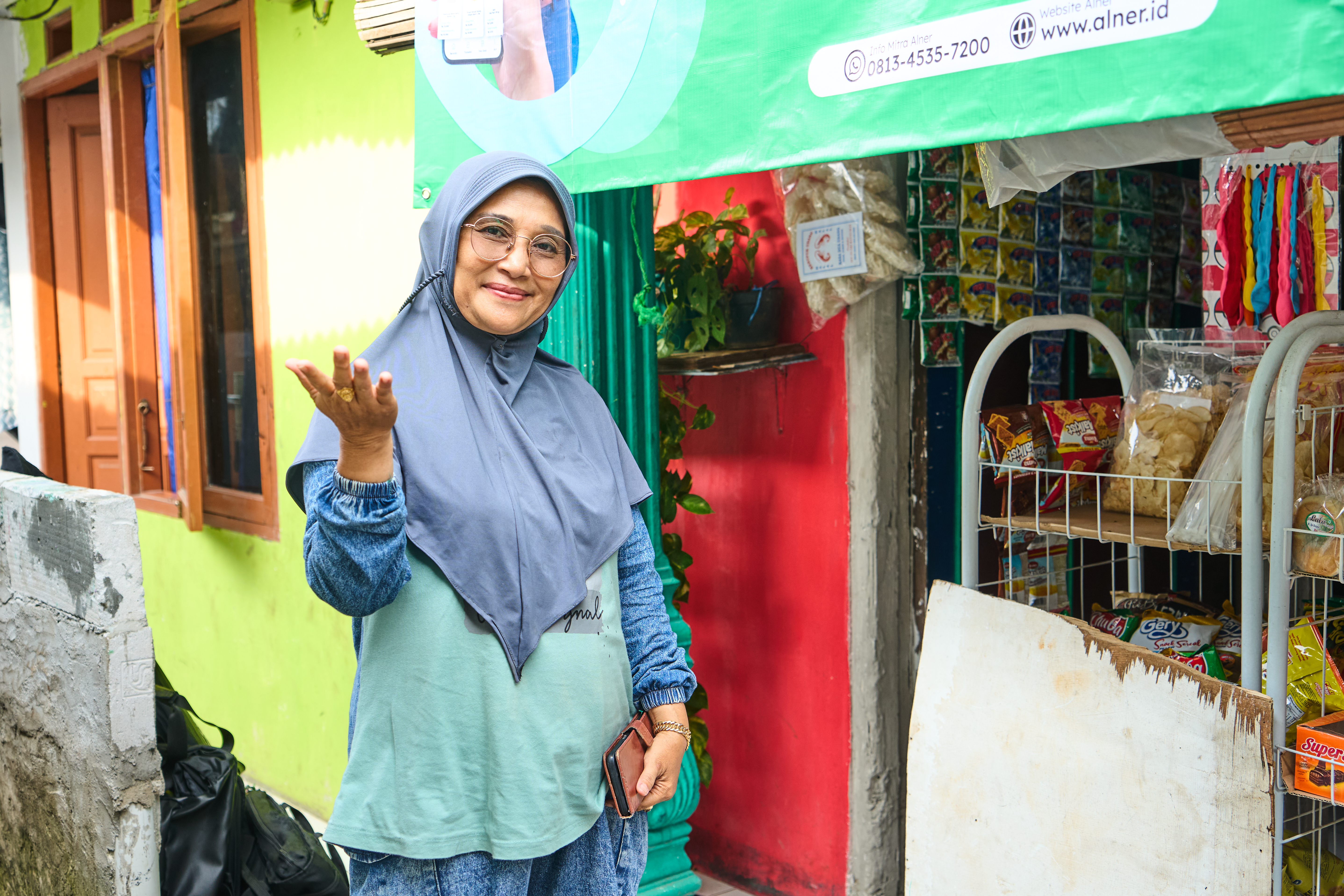 Nur, a shopkeeper in Jakarta, stands outside her shop.