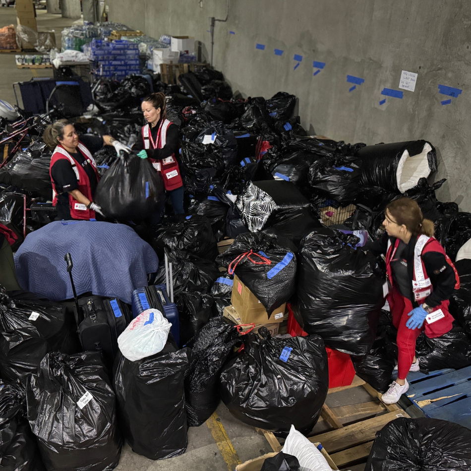 Four volunteers sort through black garbage bags of belongings left behind by shelter residents. 