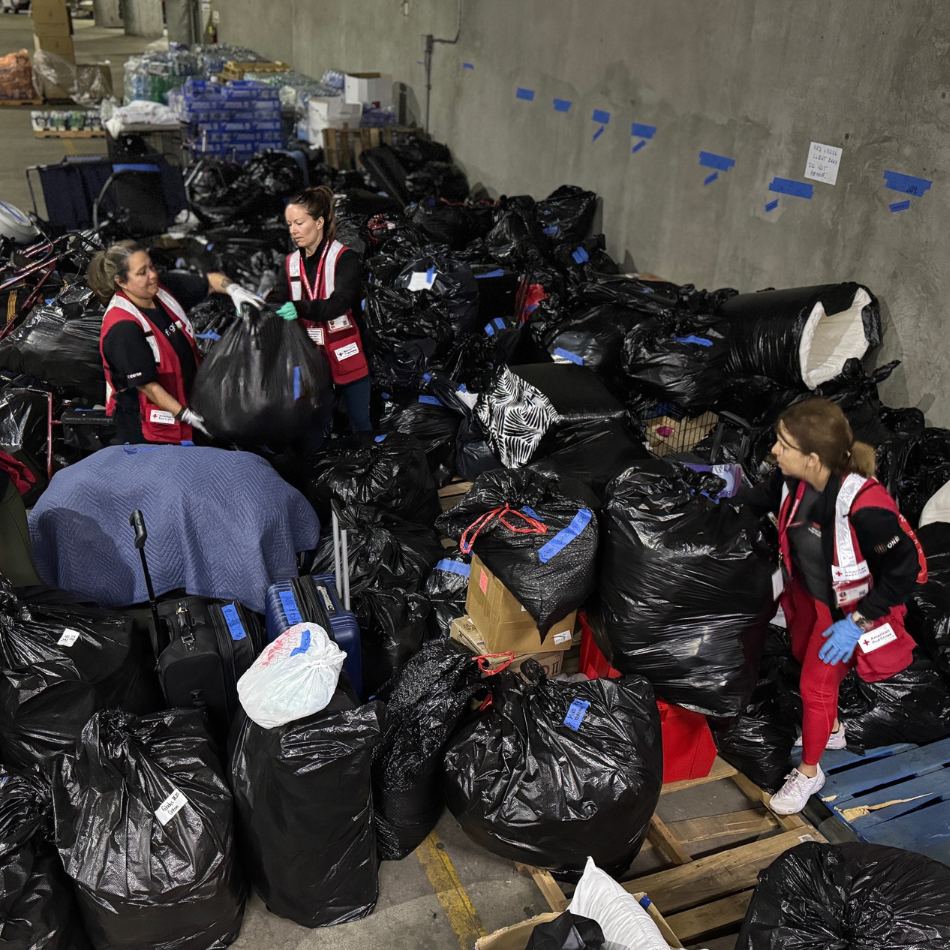 Four volunteers sort through black garbage bags of belongings left behind by shelter residents.