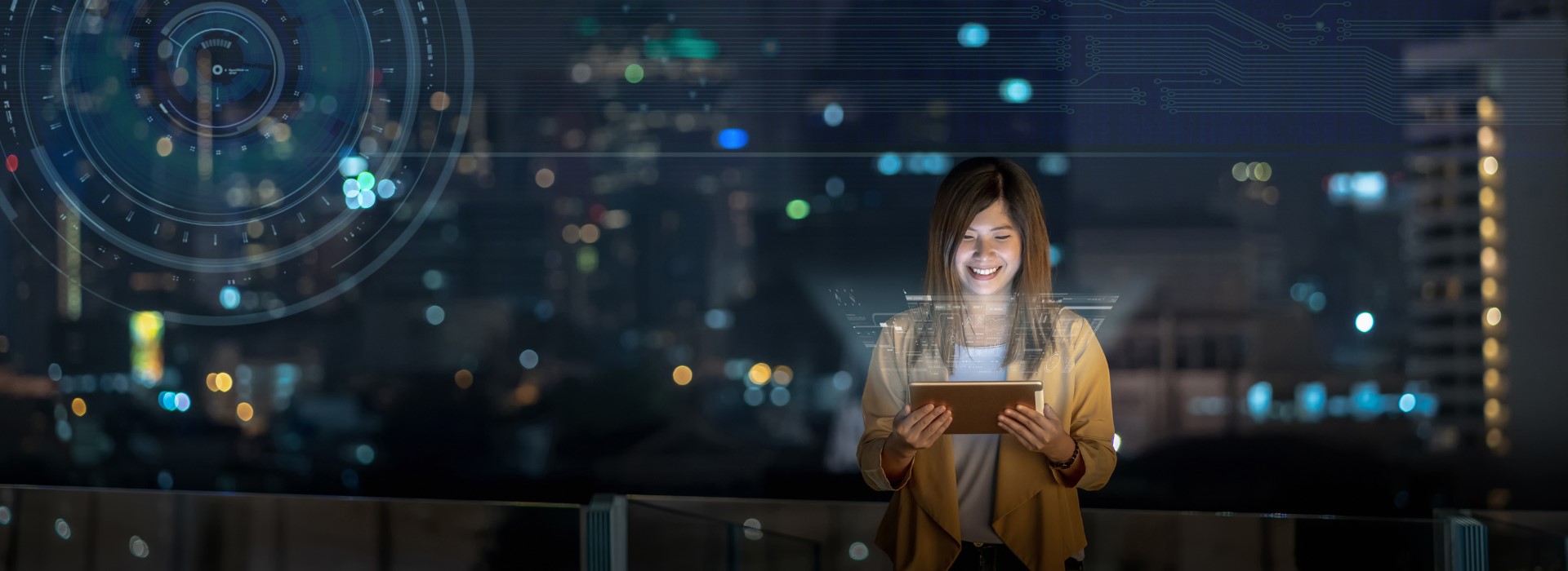 A woman smiles at her tablet at night.