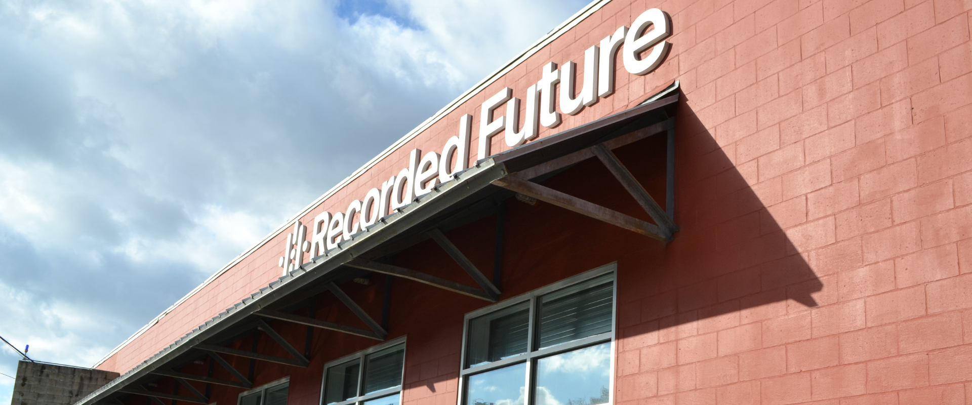 A red facade of a building with Recorded Future on it against a sky. 