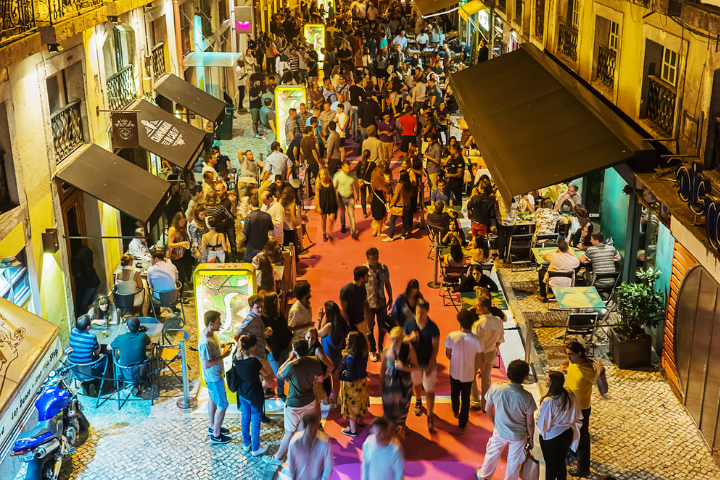 People mill around a lively street at night.