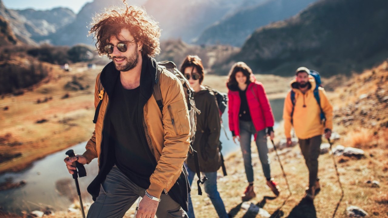 Young people hike along a river in the mountains.